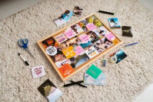 A corkboard covered in colorful images and sticky notes, surrounded by scattered crafts supplies on a soft, light-colored rug.