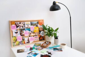 A vision board displays colorful images and notes about wellness, travel, and goals, beside a potted plant and stationery supplies.