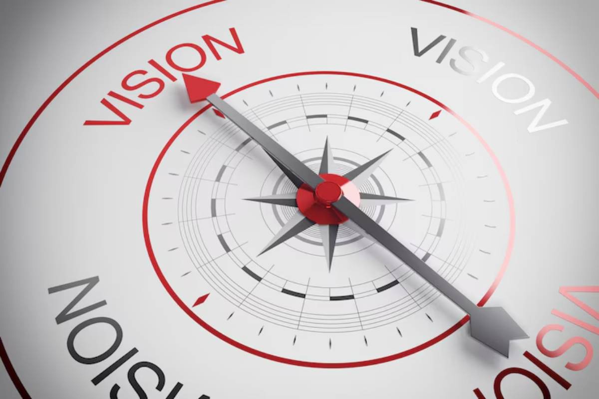 Close-up of a compass with a red arrow pointing to the word 'VISION,' symbolizing direction and clarity in goals or aspirations.