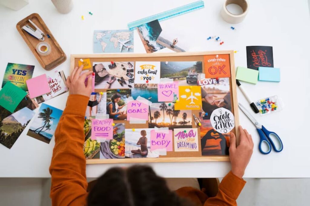 A person arranging a vision board with motivational images and sticky notes about goals, travel, and healthy living on a table.